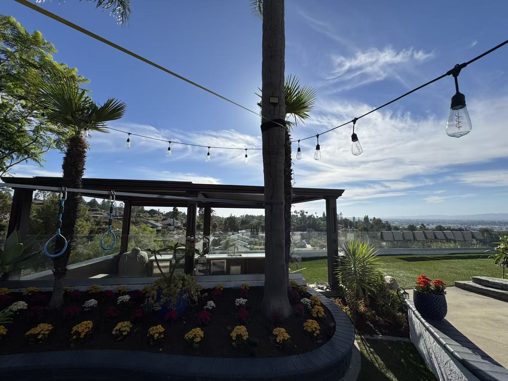 Evening view under warm string lights with the pergola sheltering the outdoor kitchen and lounge