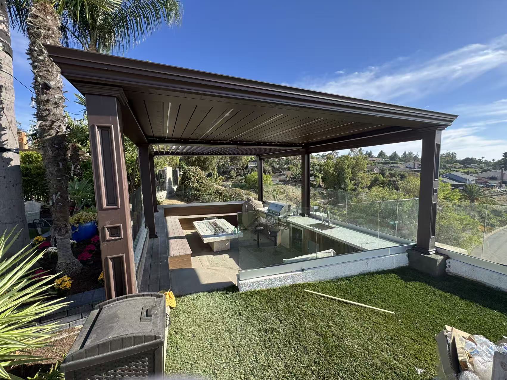 Interior view of the pergola with motorized louvers open, built-in bench and fire table above the canyon
