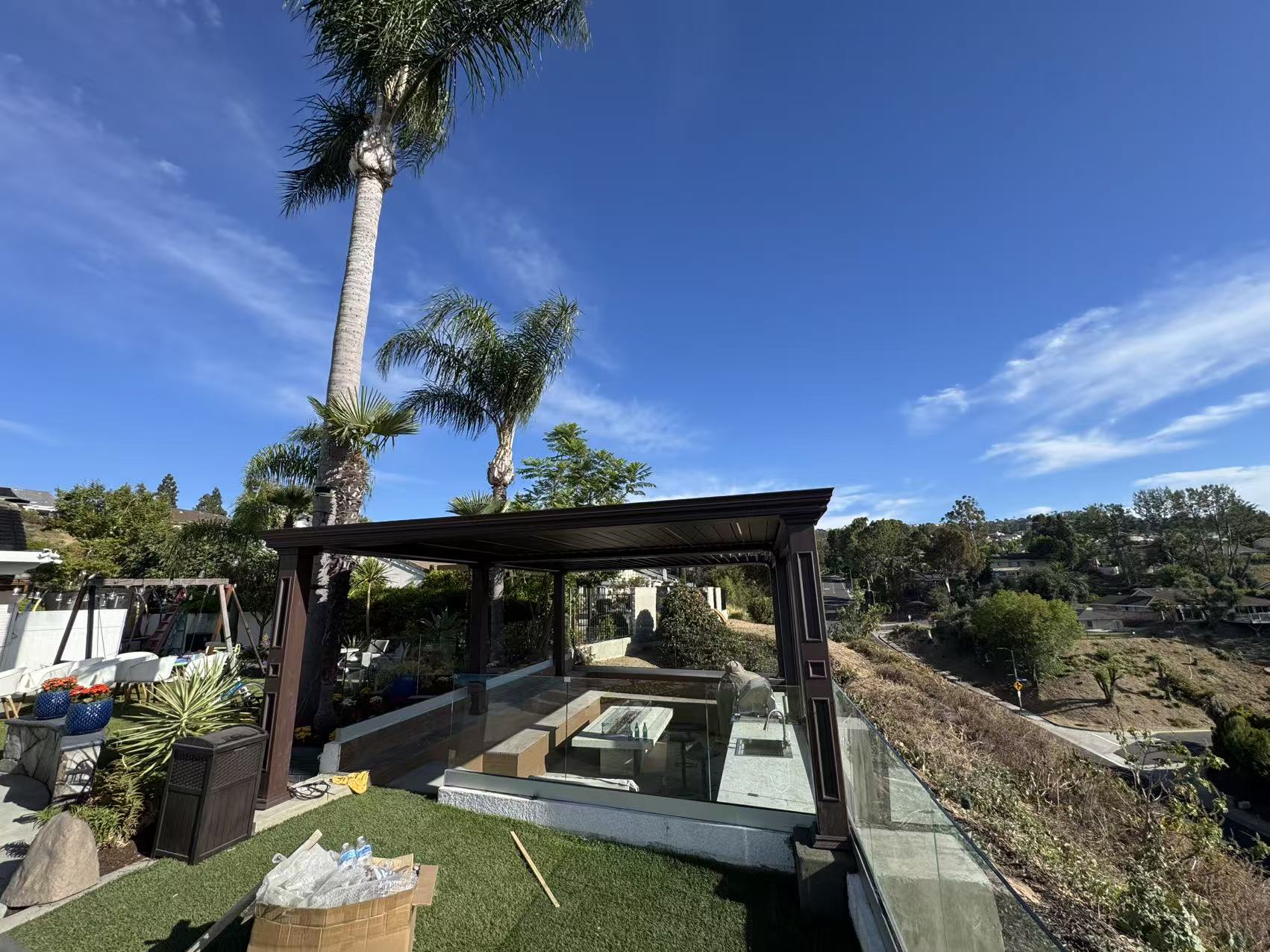 Three-quarter view of the finished pergola framing the hillside view under a clear California sky