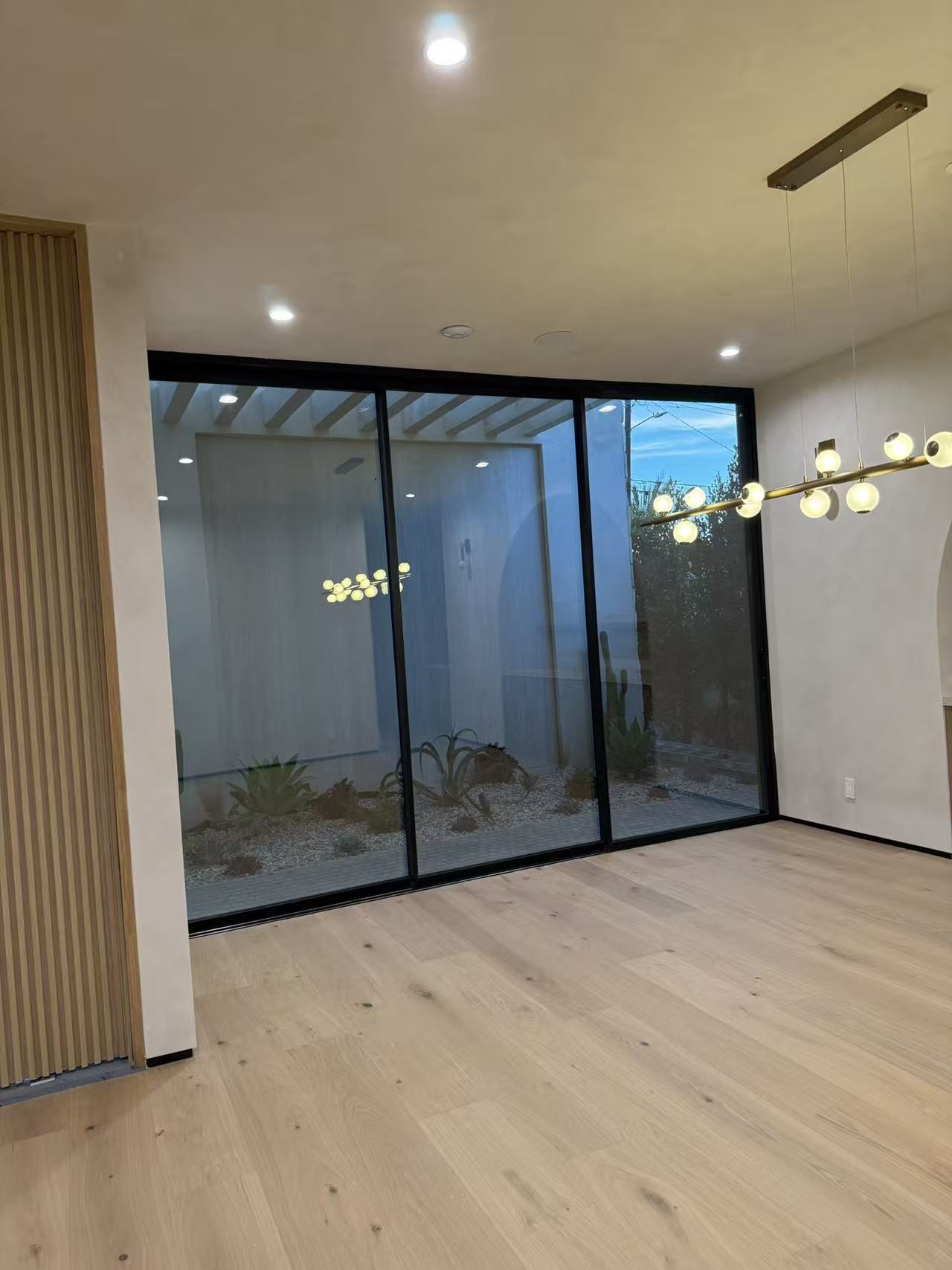 Dining area with three-panel slim-frame slider opening onto a desert courtyard