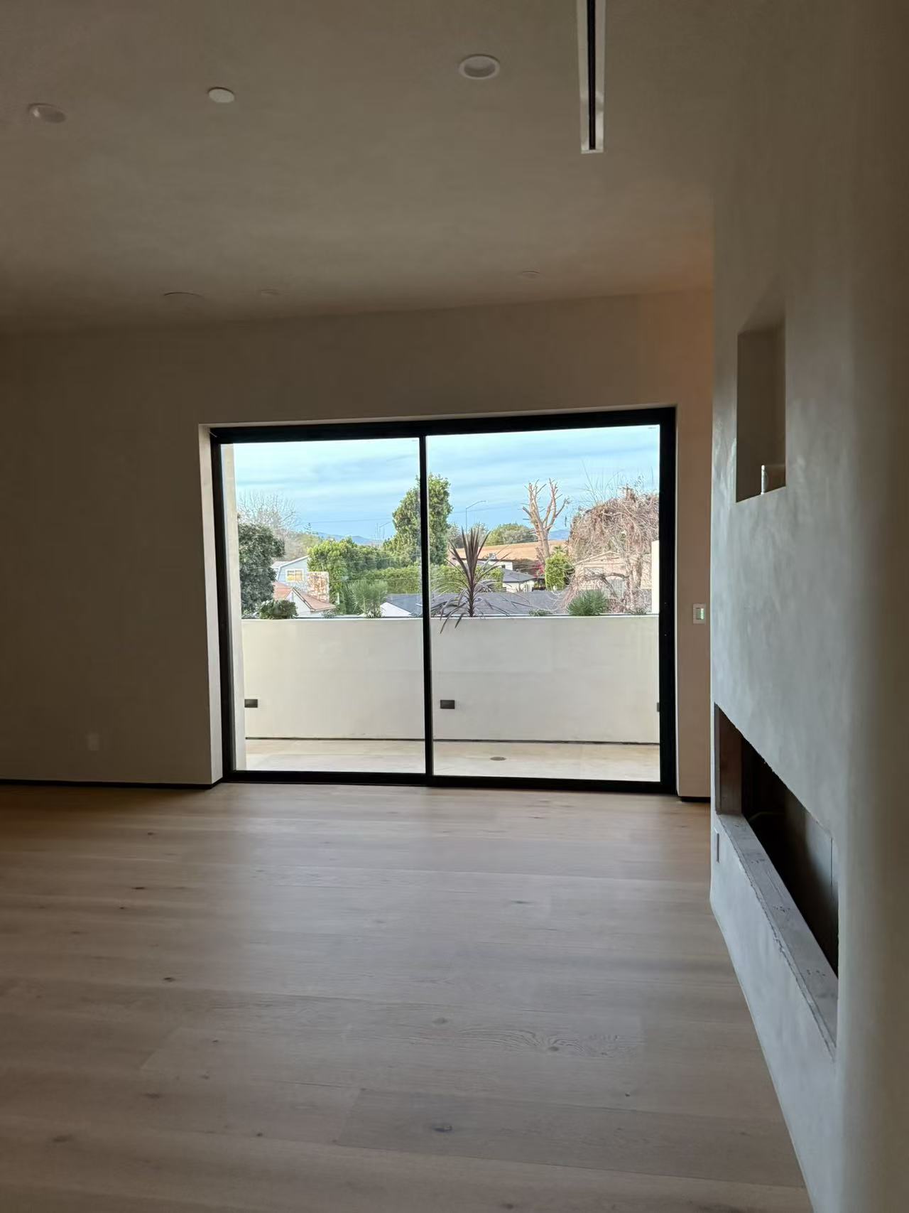 Primary bedroom with frameless slider opening to a private terrace and linear fireplace