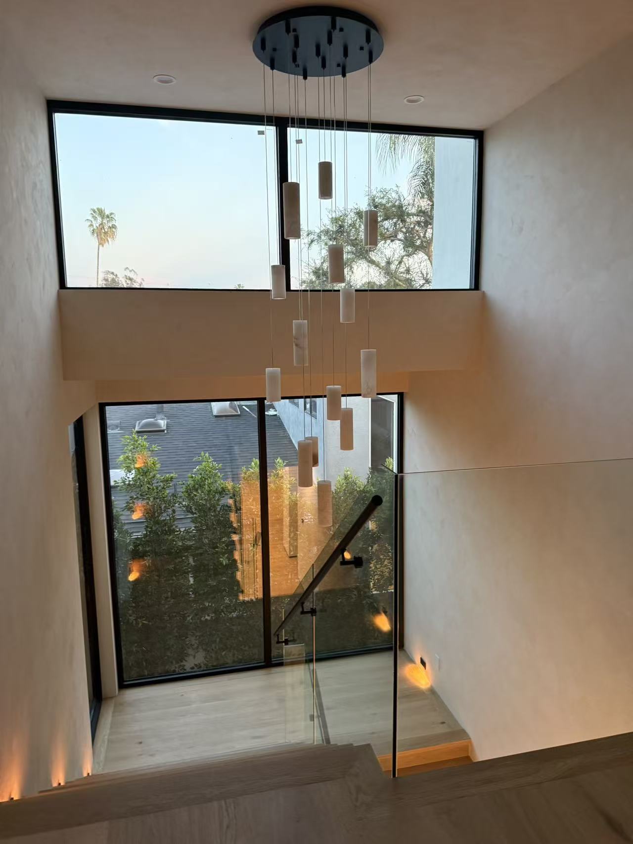 Double-height stairwell lit by clerestory windows and a cascading pendant cluster