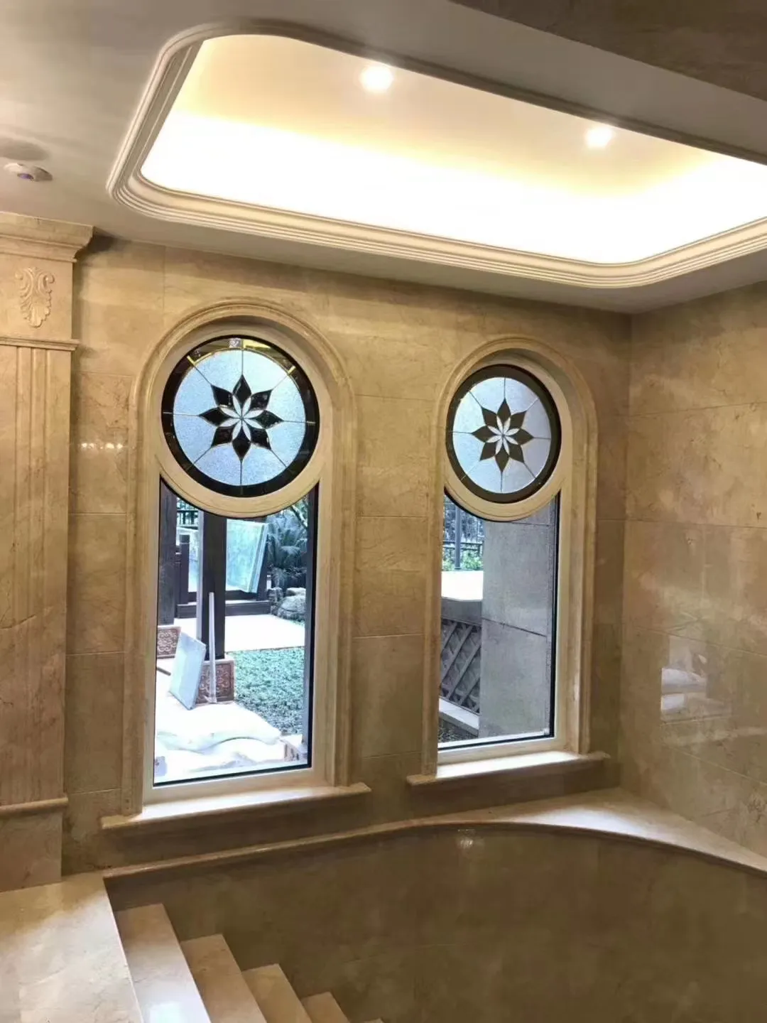 Pair of Luxora arched round-top windows with leaded glass medallions set into a travertine bath surround