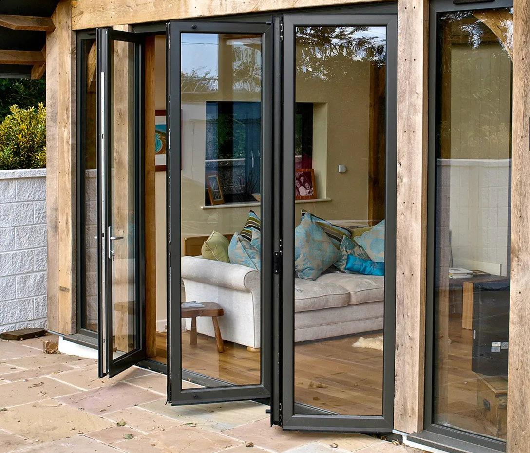 Luxora black-framed sliding folding door opening from a stone patio into a living room